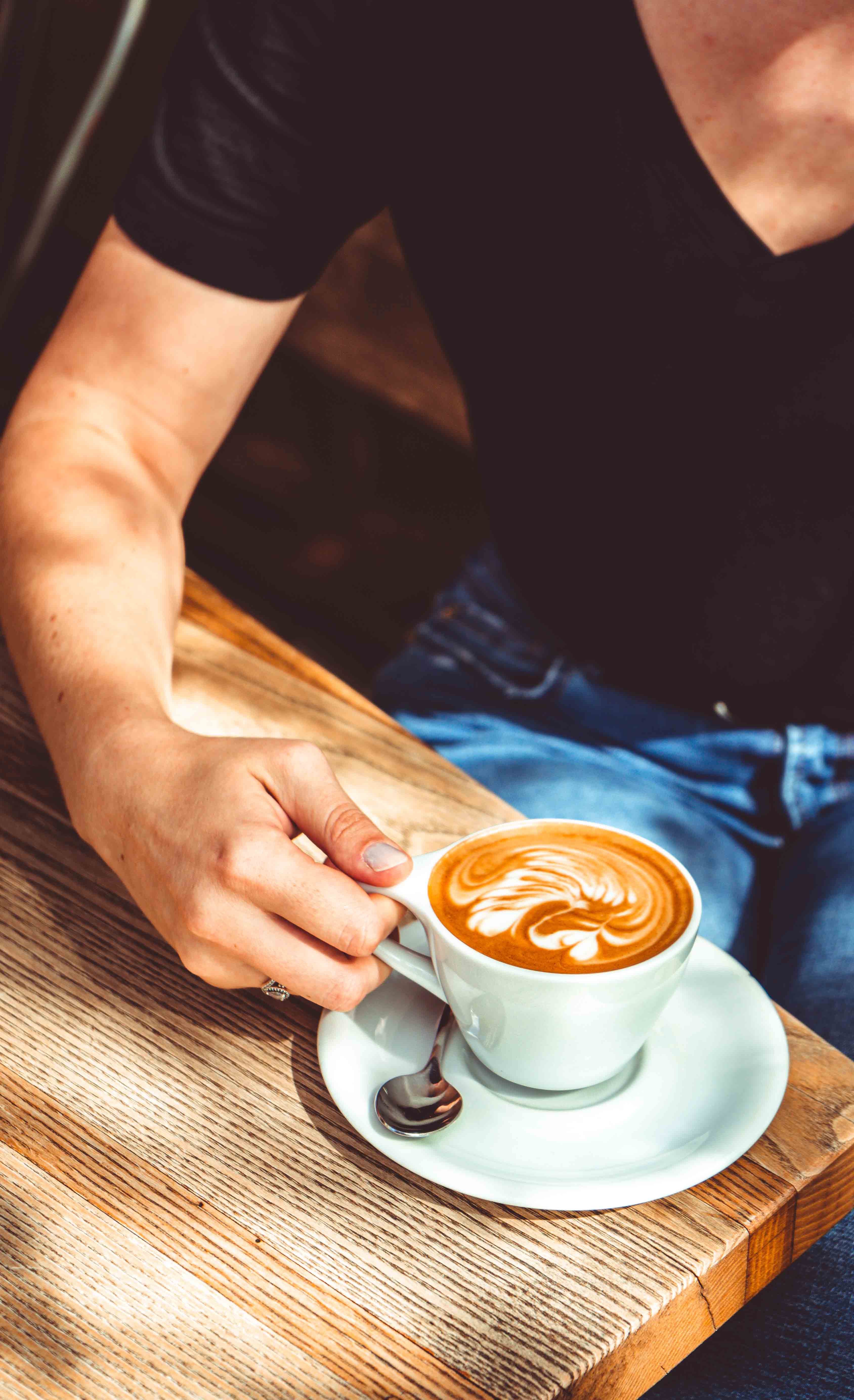 Kézben tartott latte a kávézóban
